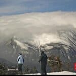 Two people standing in front of a snowy mountain in New Hampshire (NH).